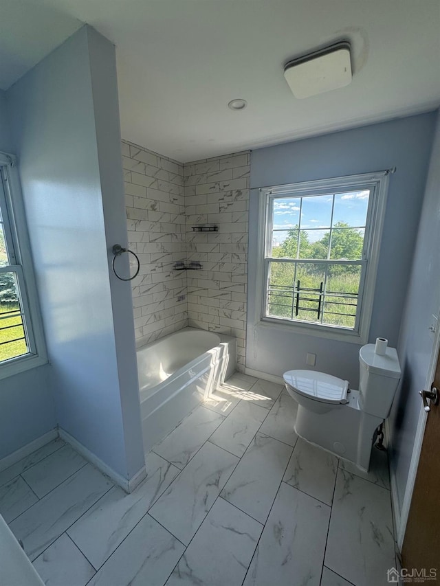 bathroom with tiled shower / bath combo, toilet, and a wealth of natural light