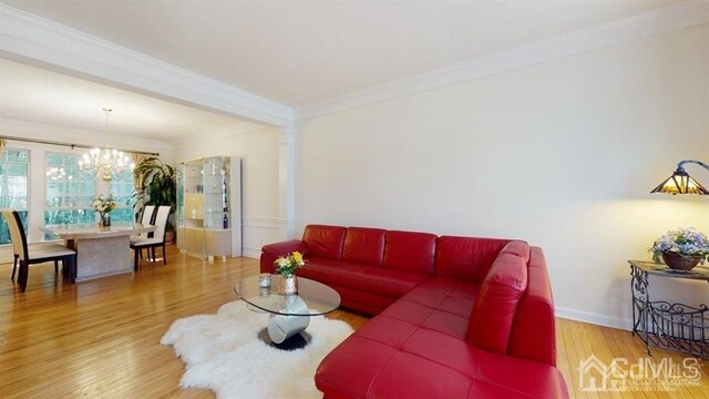 living room with ornate columns, an inviting chandelier, ornamental molding, and hardwood / wood-style flooring