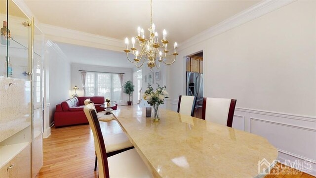 dining area featuring an inviting chandelier, light hardwood / wood-style floors, and crown molding