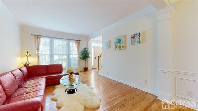 living room with decorative columns, crown molding, and light hardwood / wood-style flooring