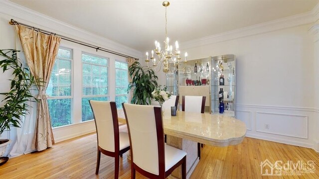 dining room with hardwood / wood-style flooring, ornamental molding, a chandelier, and plenty of natural light