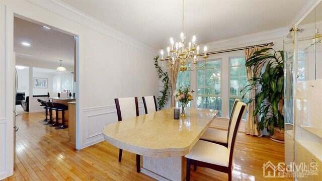 dining area featuring an inviting chandelier, crown molding, and light hardwood / wood-style flooring