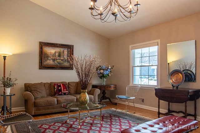 living area with baseboards, a notable chandelier, wood finished floors, and vaulted ceiling