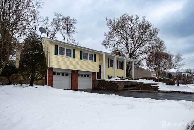 split foyer home with brick siding, an attached garage, and a chimney