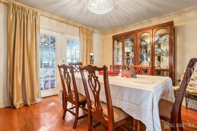 dining area with crown molding, wood-type flooring, and french doors