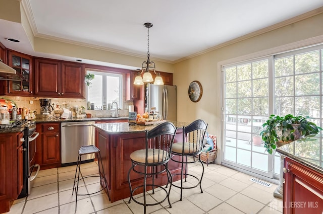 kitchen with a center island, hanging light fixtures, dark stone countertops, a kitchen breakfast bar, and stainless steel appliances