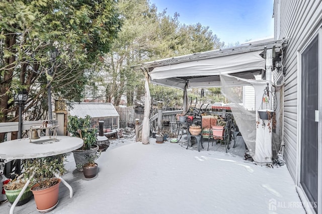 snow covered patio featuring a shed