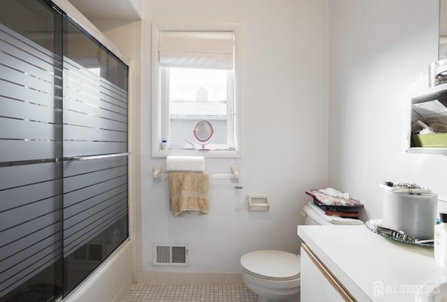 full bathroom featuring vanity, combined bath / shower with glass door, tile patterned floors, and toilet