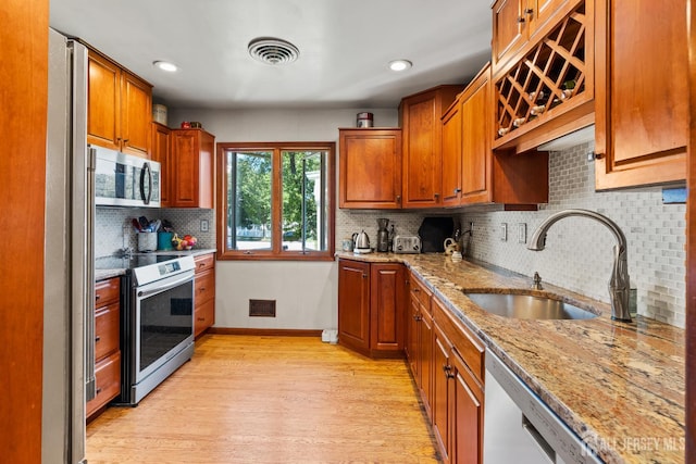 5 Meade Ct, Piscataway, NJ 08854 - kitchen featuring appliances with stainless steel finishes, light wood-type flooring, tasteful backsplash, light stone counters, and brown cabinetry