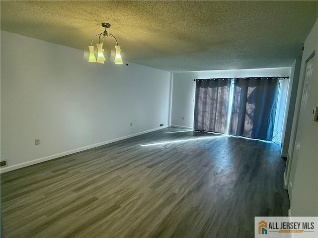 unfurnished room featuring baseboards, a textured ceiling, an inviting chandelier, and dark wood-style flooring