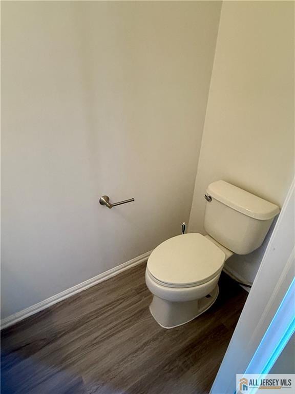 bathroom featuring toilet, wood finished floors, and baseboards