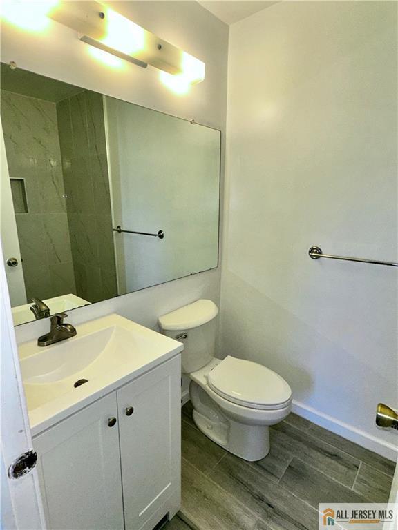 bathroom with toilet, vanity, baseboards, and wood finished floors