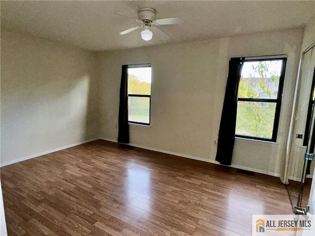 spare room with a healthy amount of sunlight, baseboards, and wood finished floors