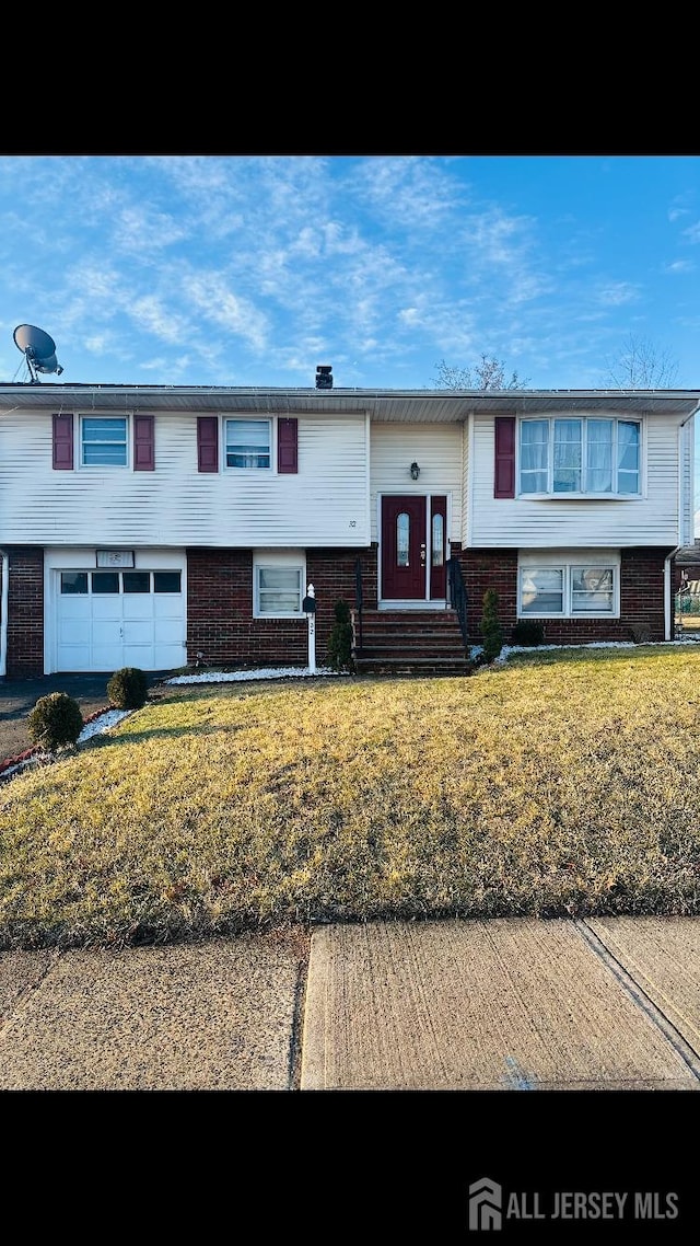 split foyer home with a garage, brick siding, and a front yard