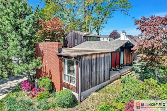 view of home's exterior featuring roof with shingles and a chimney