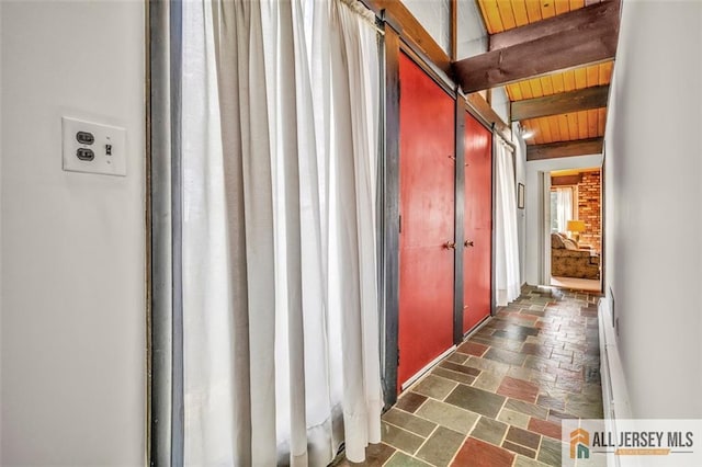 corridor with stone tile floors, wood ceiling, and beamed ceiling