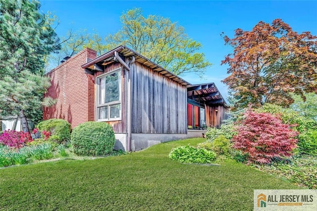 view of side of home with a lawn and a chimney