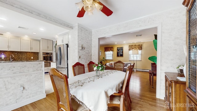 dining area with light hardwood / wood-style floors, sink, ceiling fan, a baseboard radiator, and crown molding