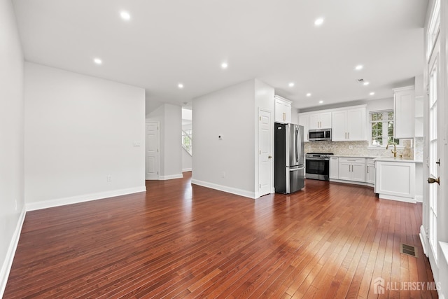19 Grossweiler Ln, Parlin, NJ 08859 - kitchen with appliances with stainless steel finishes, dark wood-type flooring, open floor plan, backsplash, and light countertops