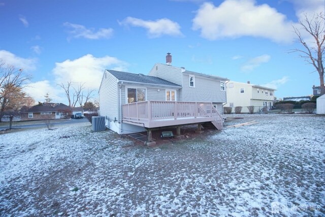 snow covered rear of property featuring a deck and central AC