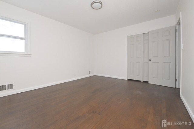 unfurnished bedroom with a closet and dark hardwood / wood-style floors