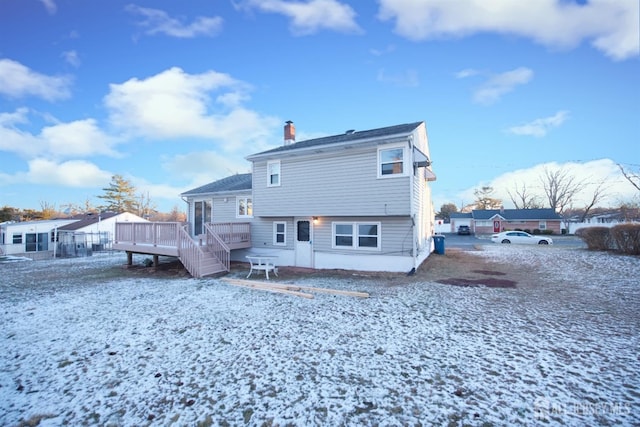 snow covered back of property featuring a deck