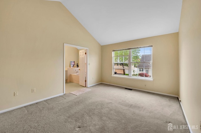 unfurnished bedroom with carpet floors, baseboards, high vaulted ceiling, and ensuite bathroom