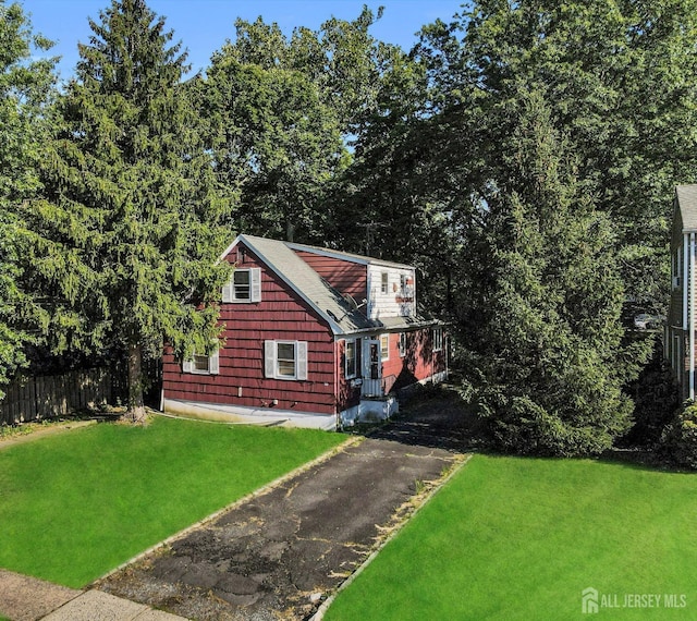 exterior space with fence, aphalt driveway, and a yard