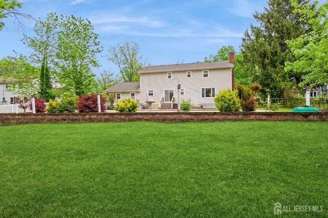 27 Briarwood Dr, Old Bridge, NJ 07747 - rear view of house with a chimney and a lawn