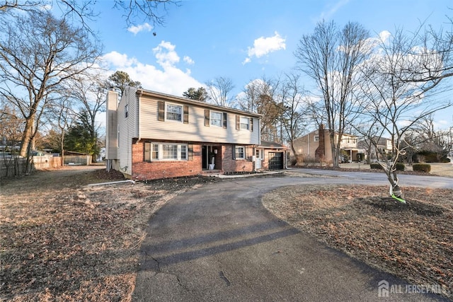 colonial inspired home with a chimney, fence, aphalt driveway, and brick siding