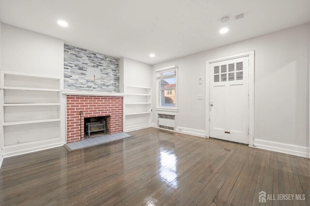 unfurnished living room featuring dark hardwood / wood-style flooring, radiator heating unit, and built in features