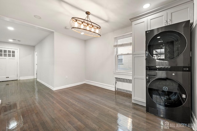 clothes washing area featuring recessed lighting, stacked washer / dryer, baseboards, radiator, and dark wood-style floors