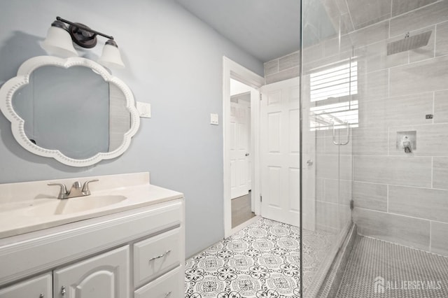 bathroom featuring a tile shower, vanity, and tile patterned floors