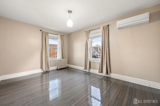 unfurnished room featuring radiator, baseboards, dark wood-type flooring, and an AC wall unit