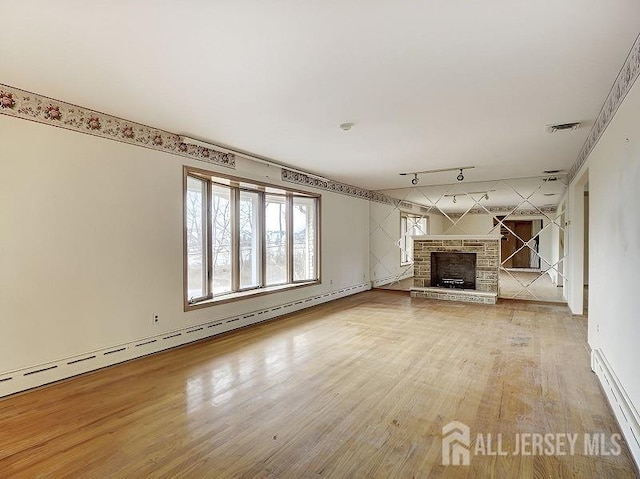 unfurnished living room featuring a baseboard radiator, light wood-style flooring, a fireplace, rail lighting, and baseboard heating