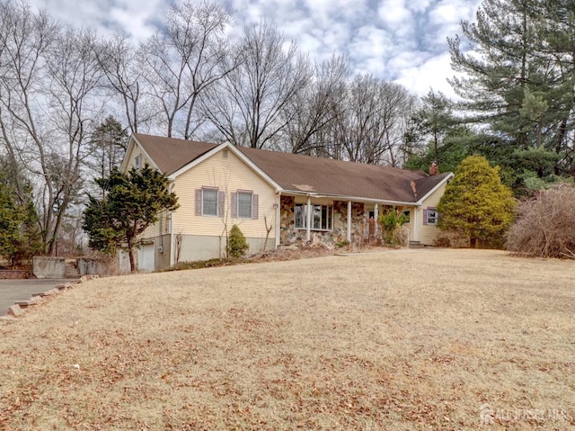 single story home with driveway, stone siding, a chimney, and a porch