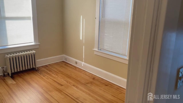 spare room featuring radiator heating unit and hardwood / wood-style floors