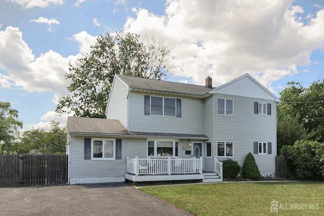 front of property featuring a wooden deck and a front lawn