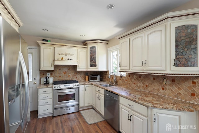 kitchen featuring backsplash, sink, dark hardwood / wood-style floors, light stone counters, and stainless steel appliances