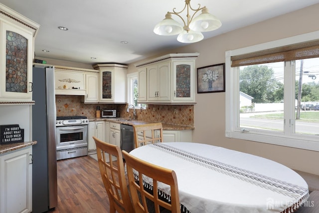 interior space with hanging light fixtures, decorative backsplash, dark hardwood / wood-style floors, stainless steel appliances, and a chandelier