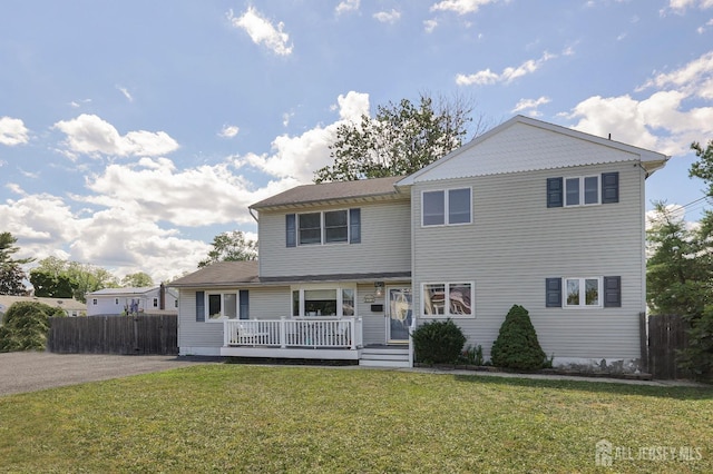 front facade with a wooden deck and a front lawn