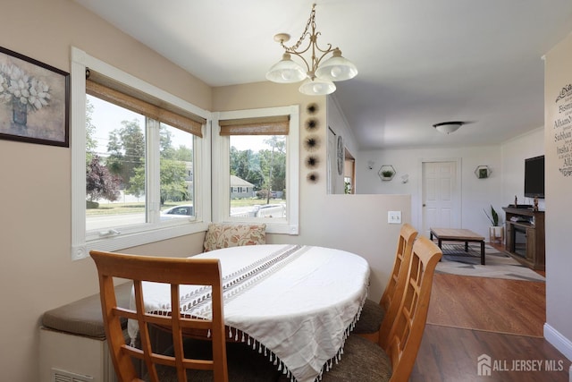 dining room with dark hardwood / wood-style flooring and an inviting chandelier