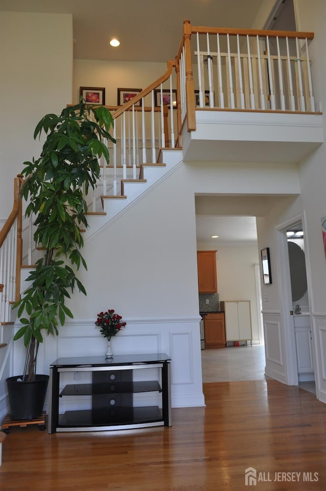 12 Sunny Ct, Monroe, NJ 08831 - stairs with a decorative wall, wood finished floors, wainscoting, a towering ceiling, and recessed lighting