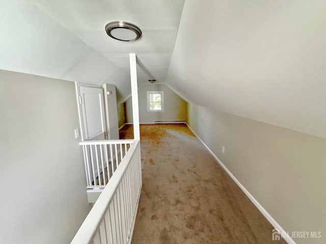 additional living space with baseboard heating, light carpet, and lofted ceiling