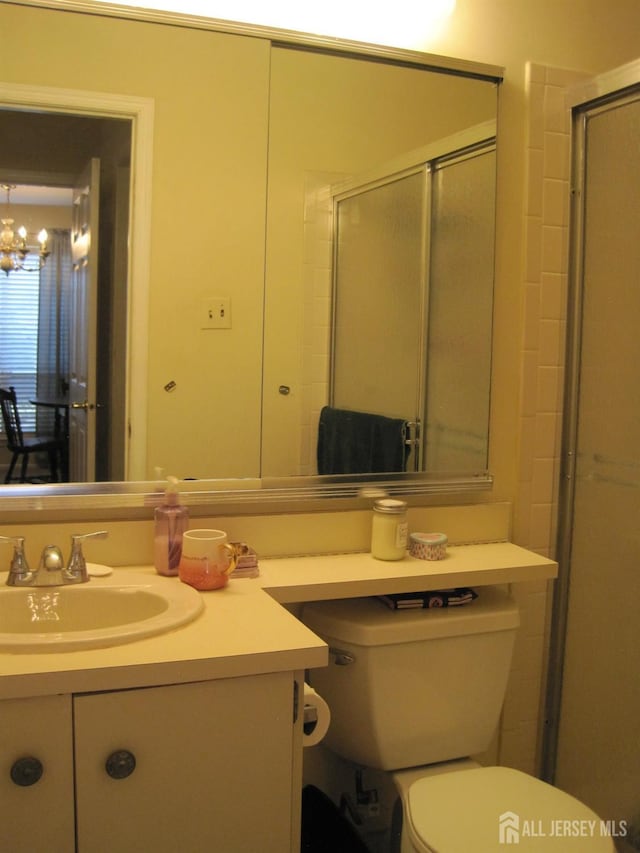 bathroom with vanity, toilet, walk in shower, and an inviting chandelier