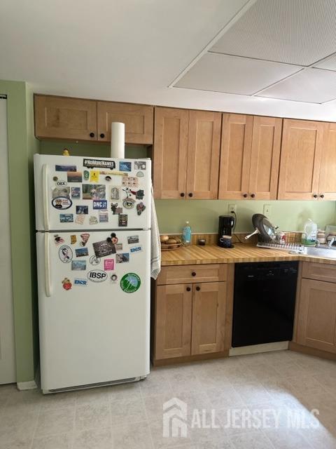 kitchen with black dishwasher, white refrigerator, and wooden counters