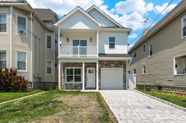 243 E 9th Ave, Roselle, NJ 07203 - view of front of house with stone siding, board and batten siding, a balcony, an attached garage, and decorative driveway
