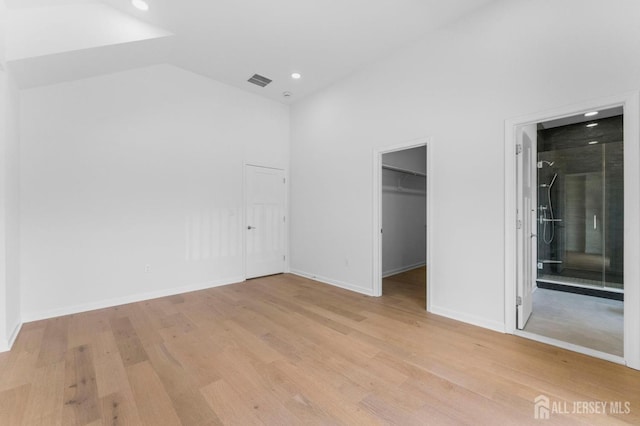 243 E 9th Ave, Roselle, NJ 07203 - unfurnished bedroom with light wood-style flooring, recessed lighting, a spacious closet, lofted ceiling, and ensuite bath