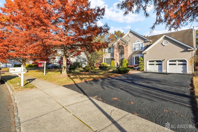 view of front of house with a garage, aphalt driveway, and a front lawn