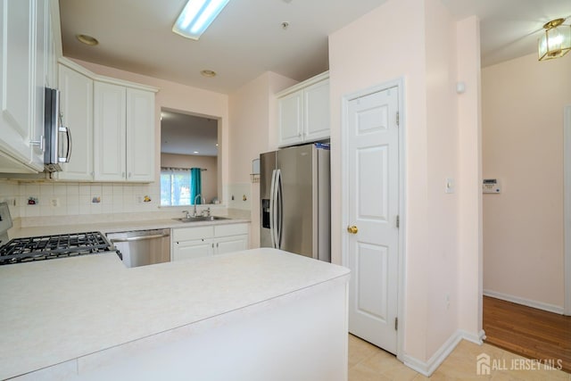 908 Blossom Cir S, Brunswick, NJ 08810 - kitchen featuring stainless steel appliances, light countertops, white cabinetry, decorative backsplash, and a peninsula